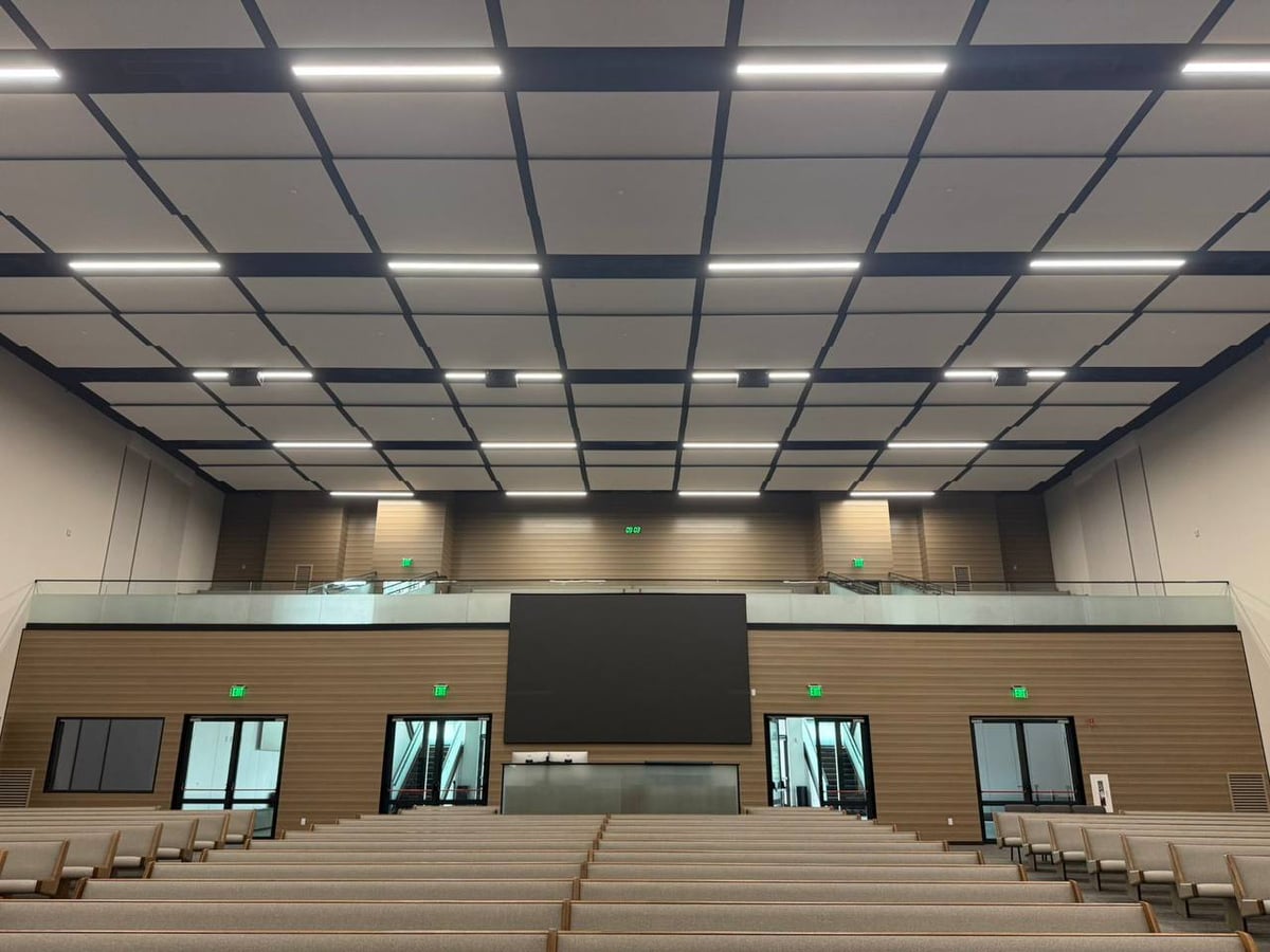 Modern church interior with grid ceiling, large screen, and rows of seating, completed by New Day Construction.