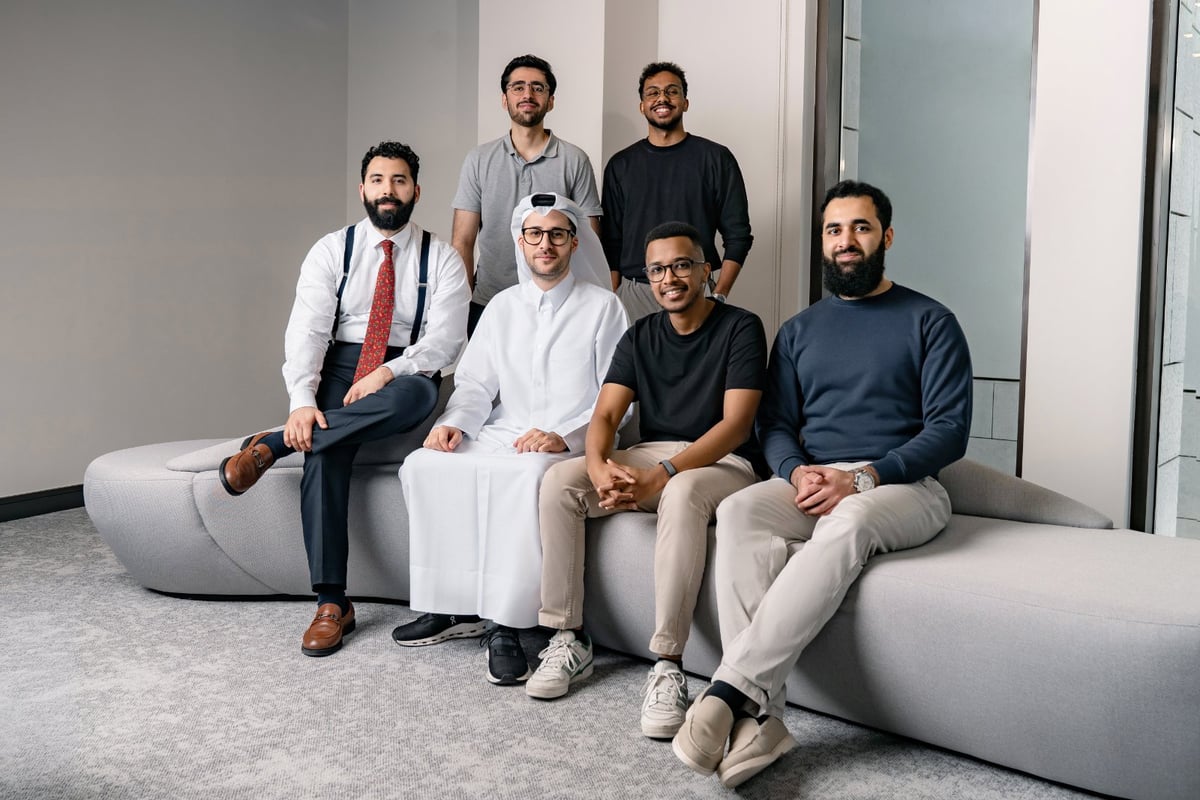 Six men, some in traditional attire and some in casual or business casual, posing and smiling for a photo.