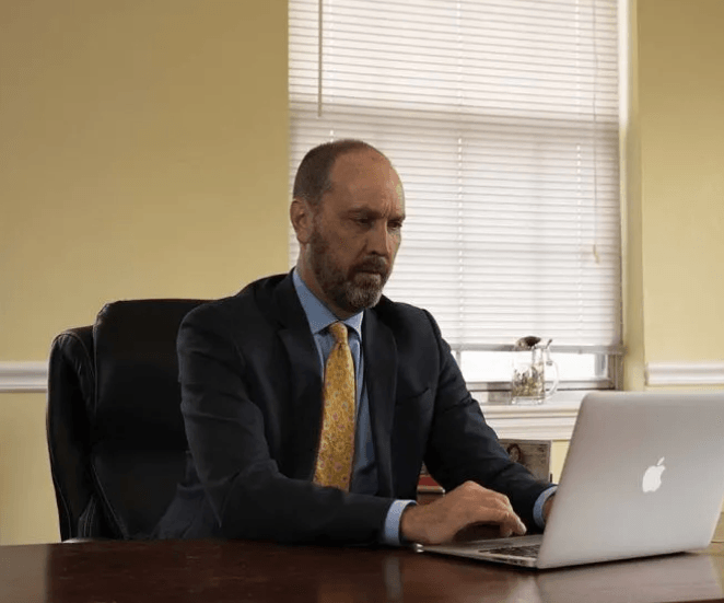 Fairfax DUI lawyer David Deane, wearing a dark suit and gold patterned tie, working on a laptop at his office desk.